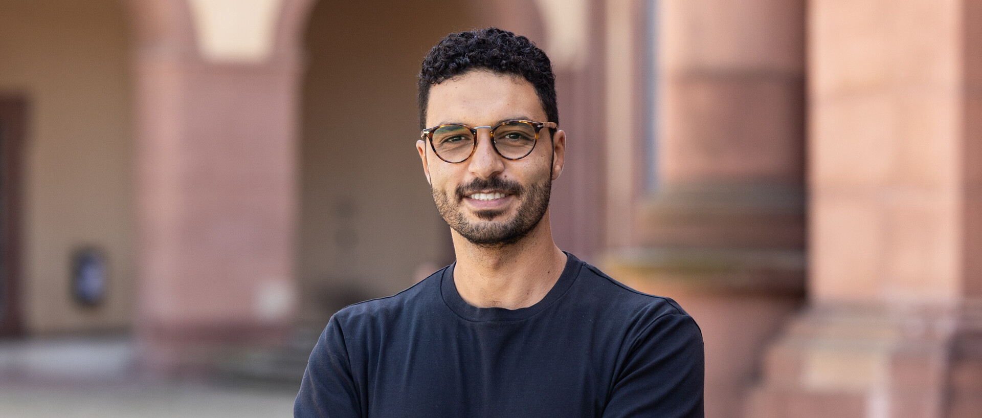 Portraitfoto von Hossam Abdellatif. Er trägt eine Brille und ein dunkelblaues T-Shirt.