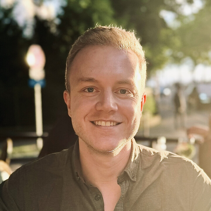 Philip Sterner hat kurze blonde Haare. Er trägt ein dunkelgrünes Hemd und lächelt in die Kamera.