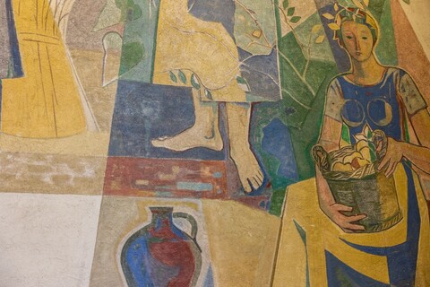 Ausschnitt einer bunten Wandmalerei: Eine Frau mit Turban trägt einen Früchtekorb.