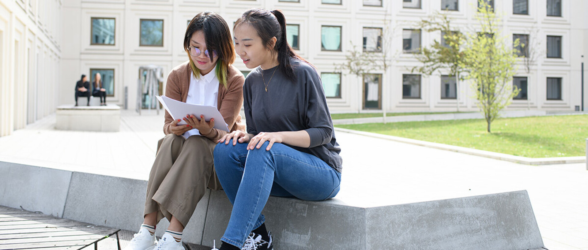 Two people reading in the yard of the university building B6