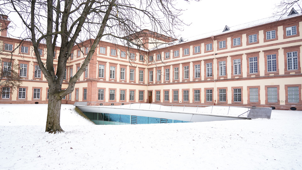 Westflügel der Universität Mannheim. Gelände ist von Schnee bedeckt.