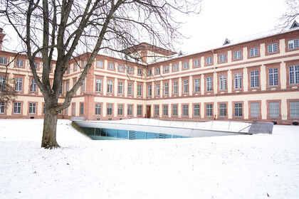Westflügel der Universität Mannheim. Gelände ist von Schnee bedeckt.