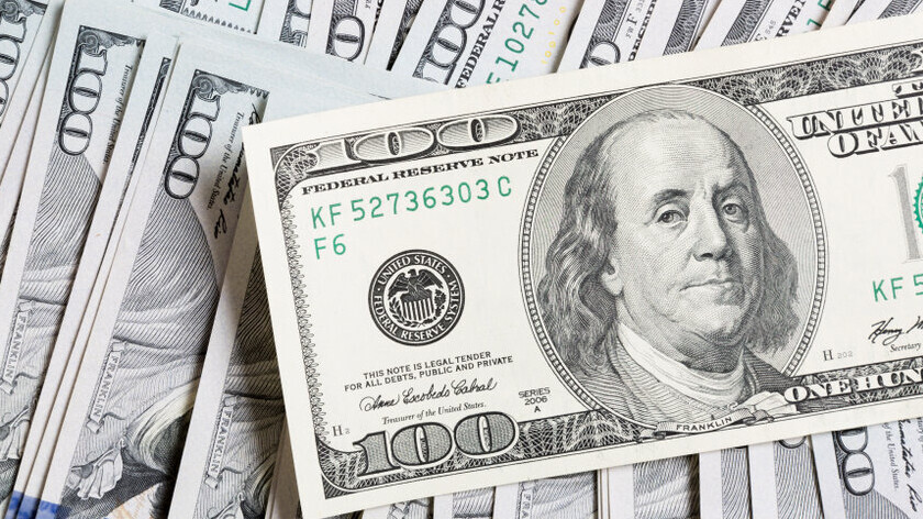 100-Dollar-Schein, im Hintergrund liegen weitere Dollar-Scheine.
