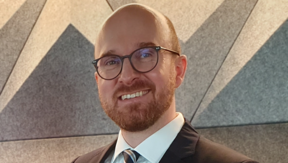 Jan-Philipp Ahrens Jan-Philipp Ahrens hat eine Glatze und einen Vollbart. Er trägt eine dunkle runde Brille, ein weißes Hemd, eine gestreifte Krawatte und ein dunkles Jackett.