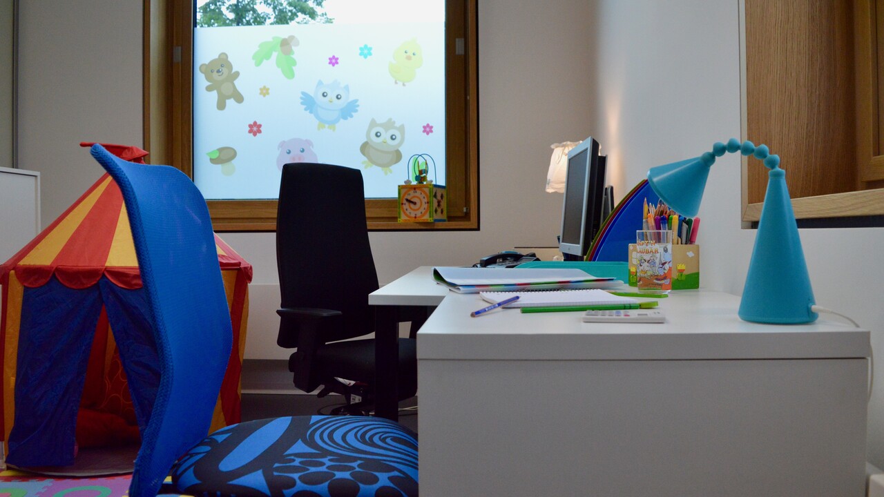 Eltern-Kind-Zimmer der Universität Mannheim. Schreibtisch mit Arbeitsutensilien. Daneben liegt ein Zelt für Kinder.