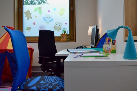 Eltern-Kind-Zimmer der Universität Mannheim. Schreibtisch mit Arbeitsutensilien. Daneben liegt ein Zelt für Kinder.
