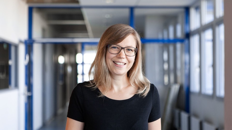 Lena Nadarevic hat helle mittellange Haare. Sie trägt eine dunkle Brille und ein schwarzes T-Shirt.