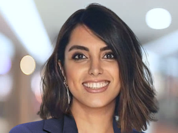 Portrait of Gholami Behnaz. She is wearing a blue blazer and standing in an office.