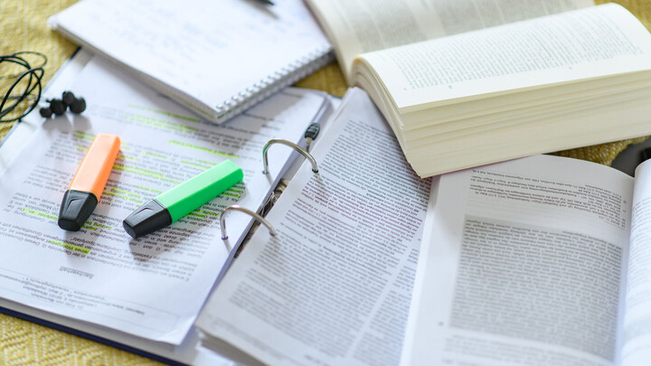 Studieren im Homeoffice Ordner, Stifte, ein Notizblock und Bücher liegen verteilt aufeinander.
