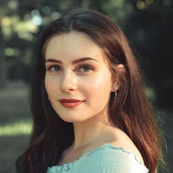 Selina Mühlberg has long brown hair and is wearing large hoop earrings. She is wearing a light turquoise top.