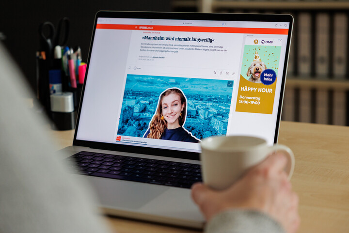 Eine Person liest einen Artikel von Spiegel Online auf einem Laptop. Dabei hält sie eine Tasse in der Hand. Man sieht die Person von hinten.