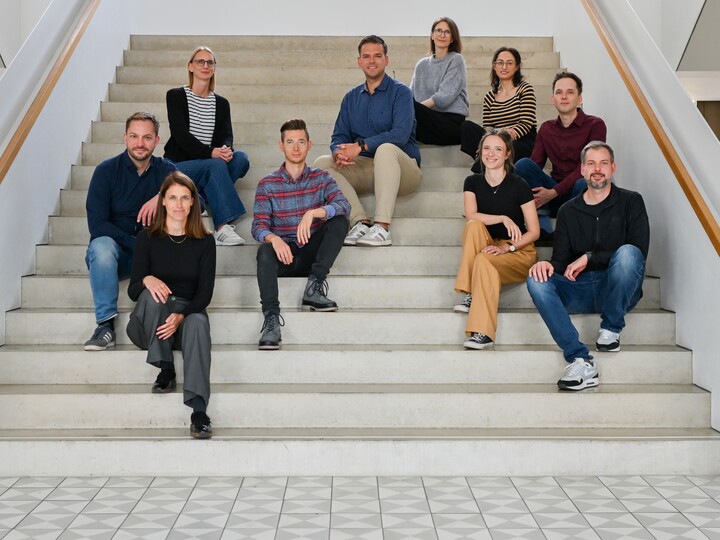 Das Team "Wandel Digital" sitzt auf einer weißen Treppe im Gebäude B6.