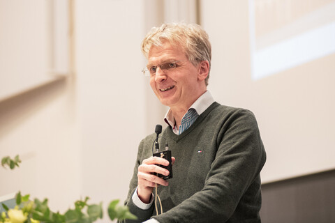 Prof. Dr. Justus Fetscher spricht auf einer Bühne mit einem Mikro in der Hand
