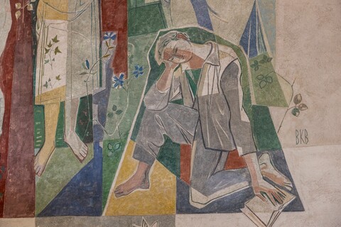 Ausschnitt einer bunten Wandmalerei: Ein Mann kniet auf einem Knie. Seine linke Hand liegt auf einem augeschlagenen Buch, mit der rechten stützt er seinen Kopf.