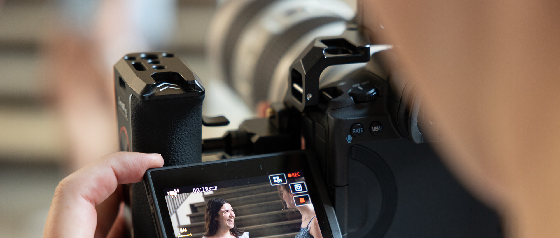 One person is holding a camera and filming two people talking
