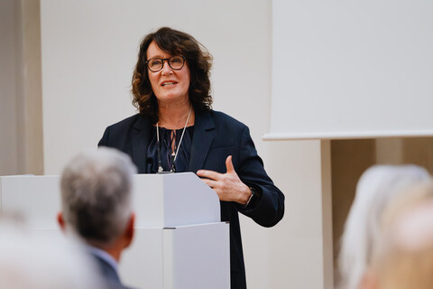Das Bild zeigt die Festrednerin Caren Sureth-Sloane am Rednerpult. Im Vordergrund sieht man den verschommenen Hinterkopf des Rektors der Universität Mannheim