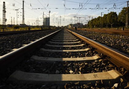 Blick auf eine Zugschiene im Abendlicht. Im Hintergrund sind ein paar Hochhausgebäude des Mannheimer Bahnhof erkennbar.