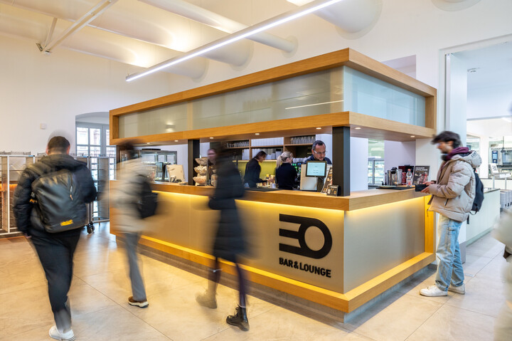 Ein Student bestellt etwas an der Theke der EO Bar&Lounge. Weitere Studierende laufen an der Theke vorbei.
