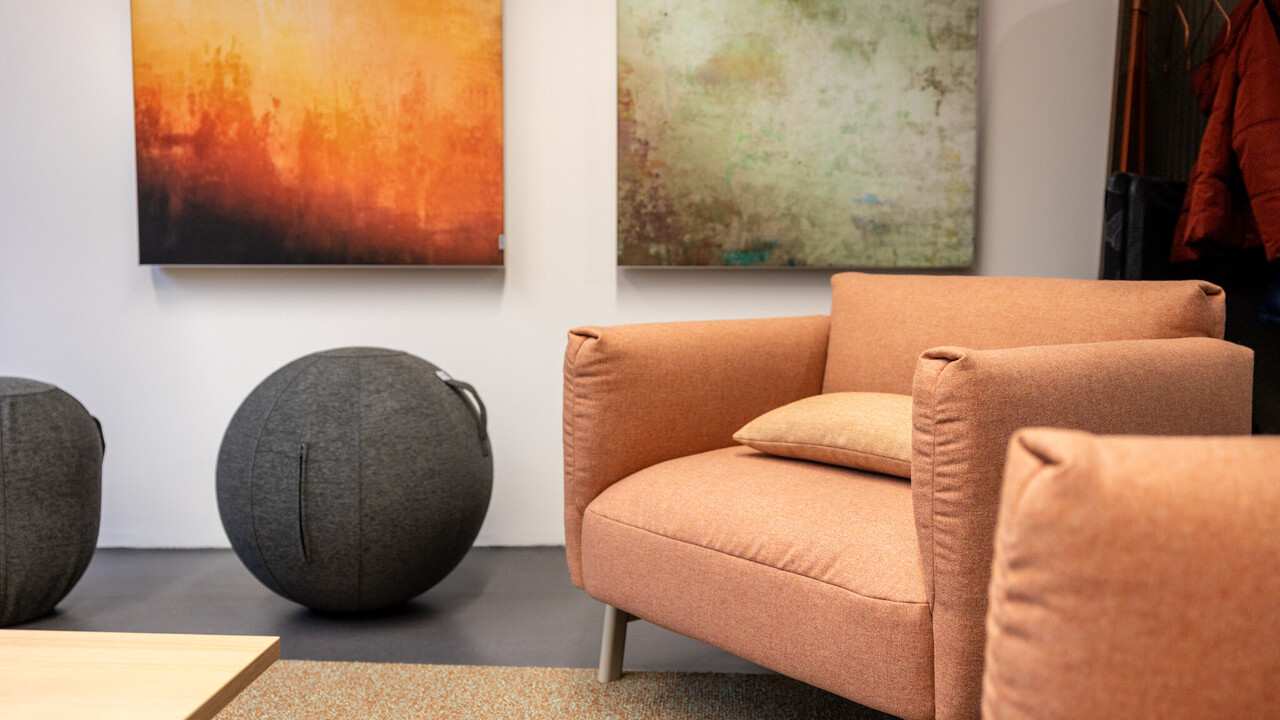 Das BIld zeigt einen erdtonfarbenen Sessel und einen stoffbezogenen grau-melierten Sitzball.