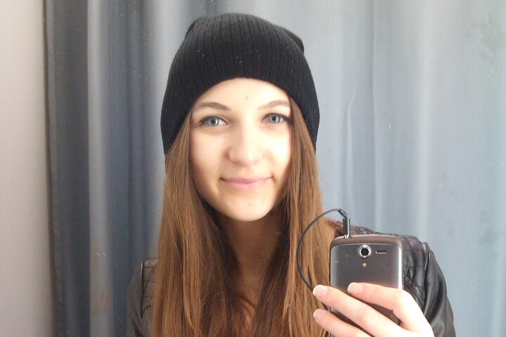 Gabrielė Zebrovskyte macht ein Foto von sich im Spiegel und lächelt in die Kamera. Sie hat lange braune Haare und trägt eine schwarze Mütze und eine Lederjacke. 