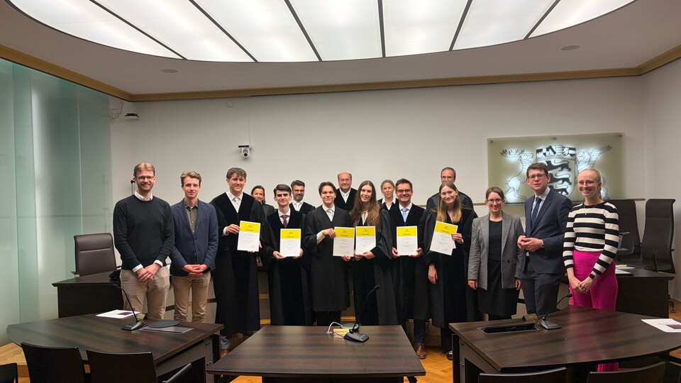 Eine Gruppe der Teilnehmenden am Moot Court zeigt lächelt in die Kamera und zeigt die Urkunden