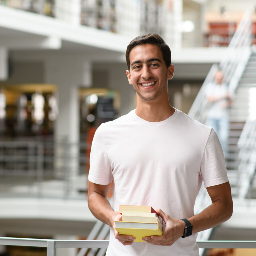 Ein Student steht im Bibliotheksbereich in A3. 