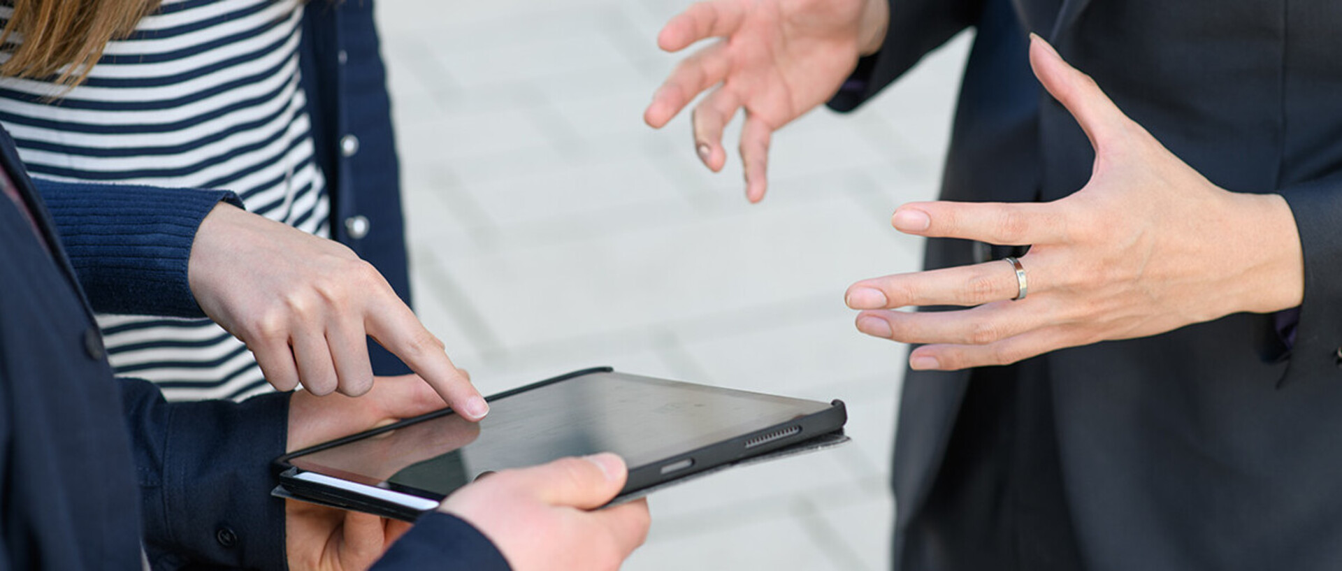 Three people are pointing at a tablet and are discussing a dissertation proposal.