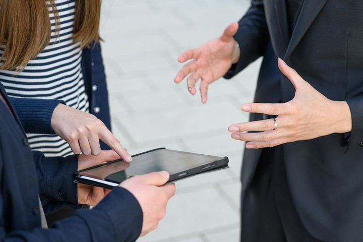 Three people are pointing at a tablet and are discussing a dissertation proposal.