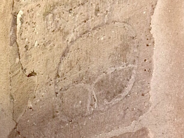 Eine in eine steinerne Außenmaußer eingeritzte Bretzelform.