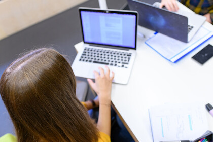 Eine Studentin liest ein Dokument auf ihrem Laptop.