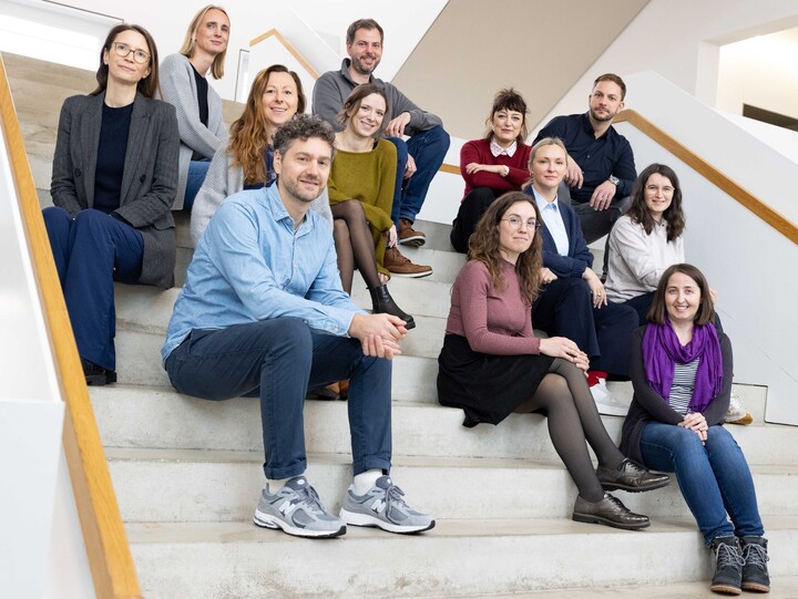 12 Leute sitzen auf einer weißen Treppe im Gebäude B6. 