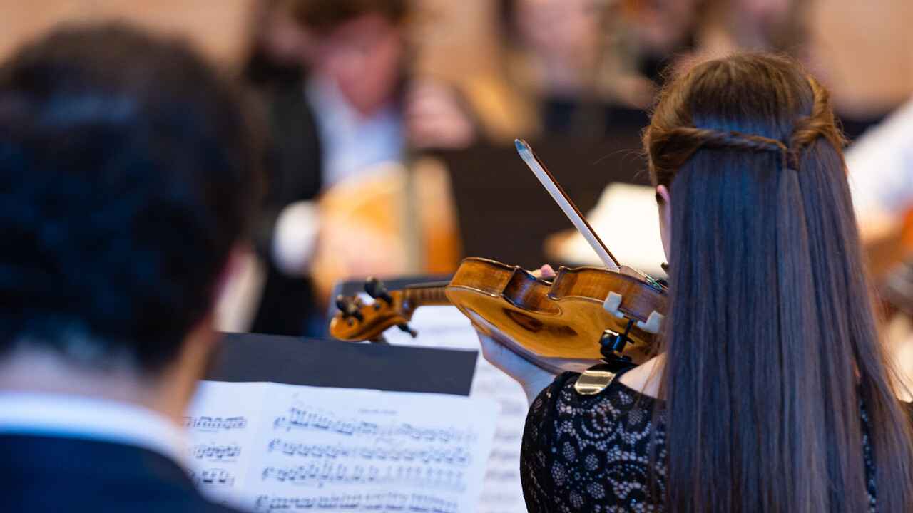 auftritt des Uniorchesters. Studierende sind schwarz gekeidet und spielen jeweils ein Instrument.