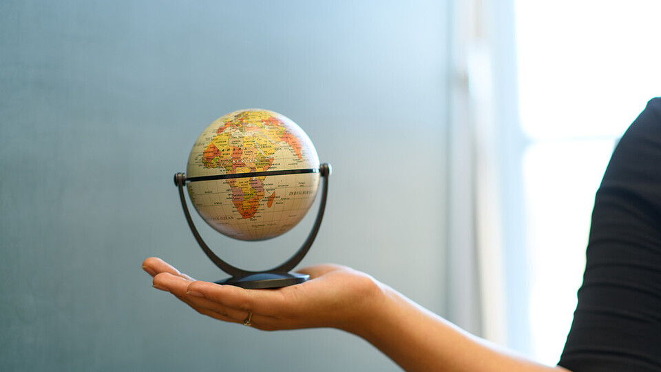 Ein kleiner Globus, der von einer Hand hochgehalten wird.