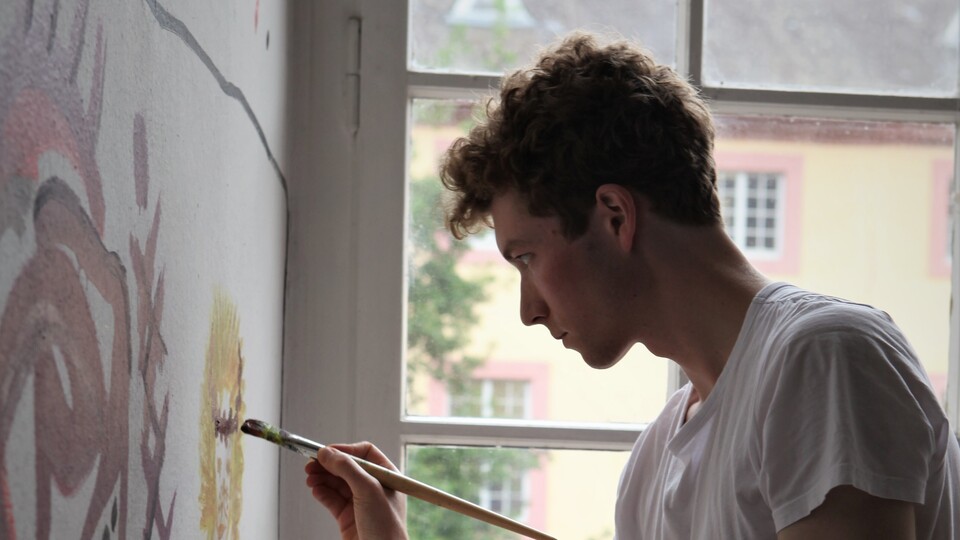 Eine Person malt auf eine Wand.
