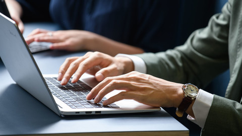 Ein Student tippt auf seinem Laptop an seinem Arbeitsplatz.