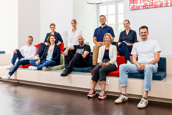 Ein Gruppenfoto der neun Mitglieder des KI-Kernteams. Sie schauen alle lächelnd in die Kamera.