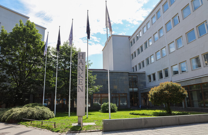 Die Hanken School of Economics von außen, umgeben von einer Rasenfläche auf welcher fünf Fahnen stehen. 