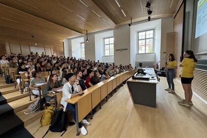Studierende sitzen in einem Hörsaal und schauen auf die Powerpoint-Präsentation an der Wand.