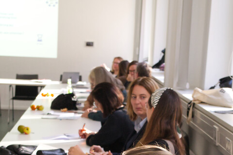 Eine Teilnehmerin schreibt Diskussionsergebnisse mit einem Marker auf buntes Papier.