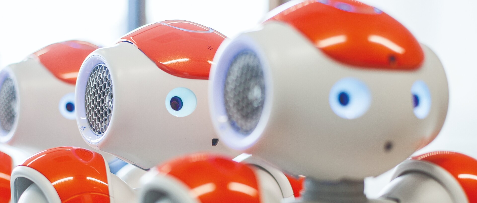 Drei orange-weiße Roboter stehen in einer Reihe hintereinander.