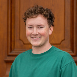 Felix Forner. Die Person steht vor dem Schloss und trägt ein grünes T-Shirt.