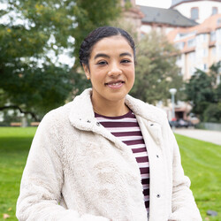 Studentin steht vor einem Park in der Innenstadt