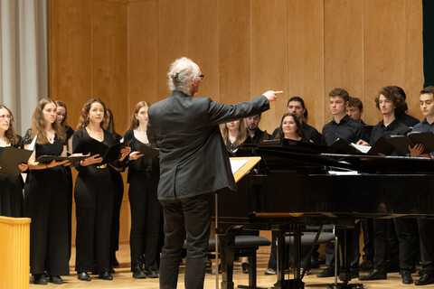 Ein Chorleiter dirigiert seinen Chor während einer Aufführung.