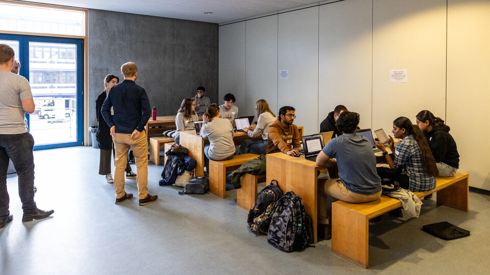 Eine große Gruppe Studierende arbeitet an Tischen im Foyer