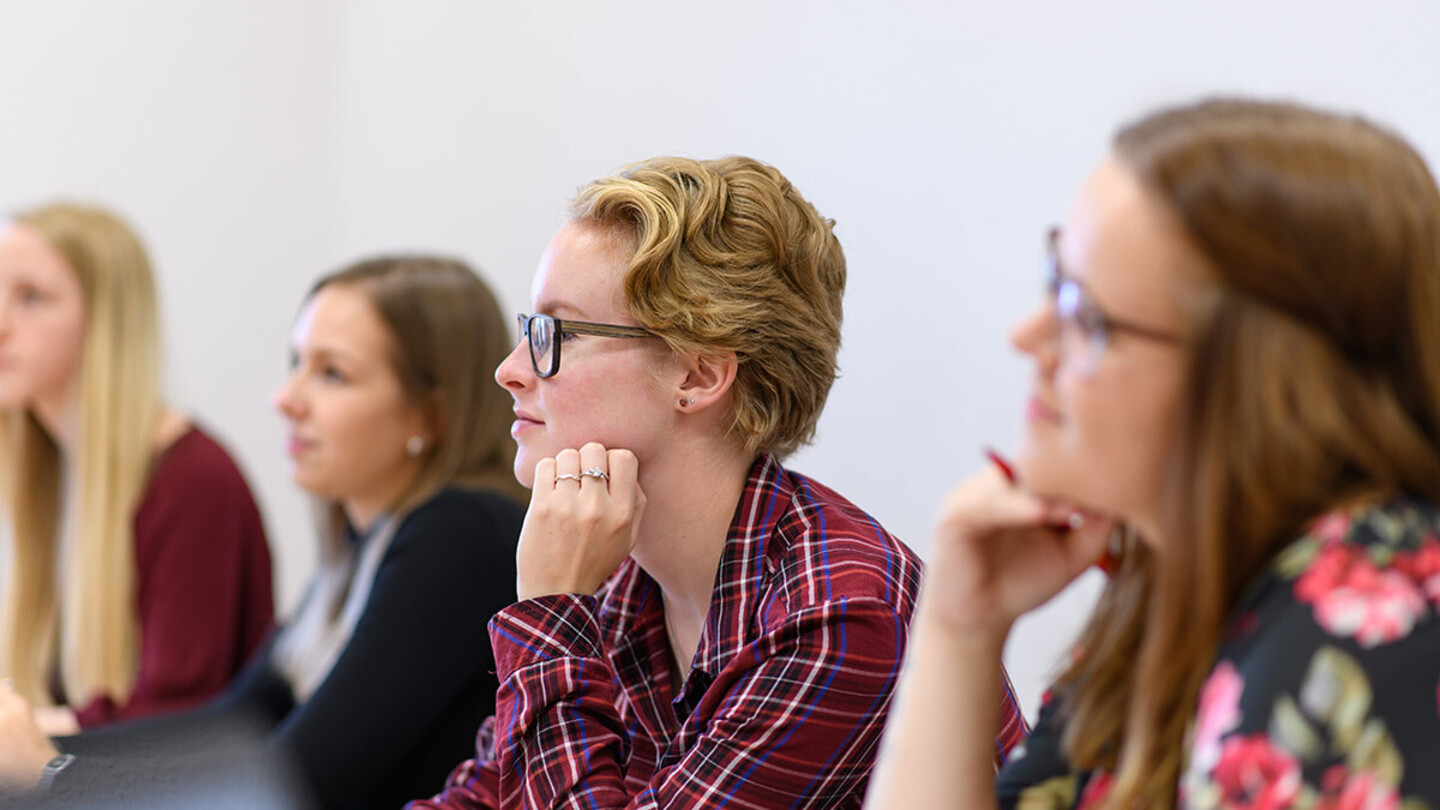 Studentinnen hören bei einem Vortrag zu.