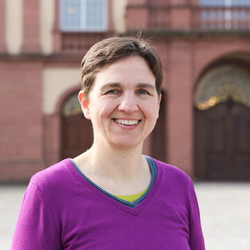 Maren Kloppenburg hat kurze braune Haare. Sie trägt einen lilafarbenen Pullover mit V-Ausschnitt.