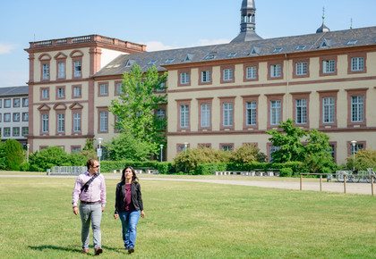 Zwei Personen laufen über die Wiese vor dem Mannheimer Schloss, dem Sitz der Universität Mannheim