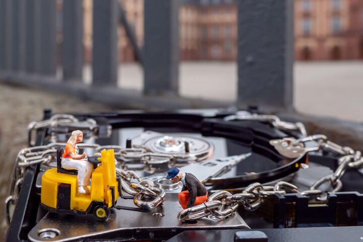 Auf dem Bild verschlüsseln zwei Miniaturfiguren eine Fesplatte. 