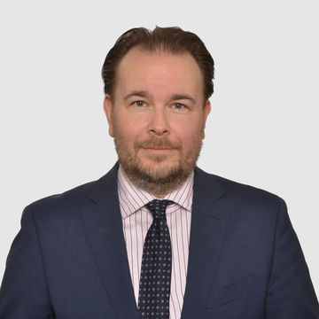 Prof. Danke hat kurze Haare und trägt Bart. Er trägt ein dunkelblaues Jacket, ein helles Hemd und eine dunkle Krawatte.
