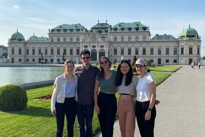 Fünf lächelnde Personen stehen nebeneinander in einem Schlossgarten vor einem Schloss.